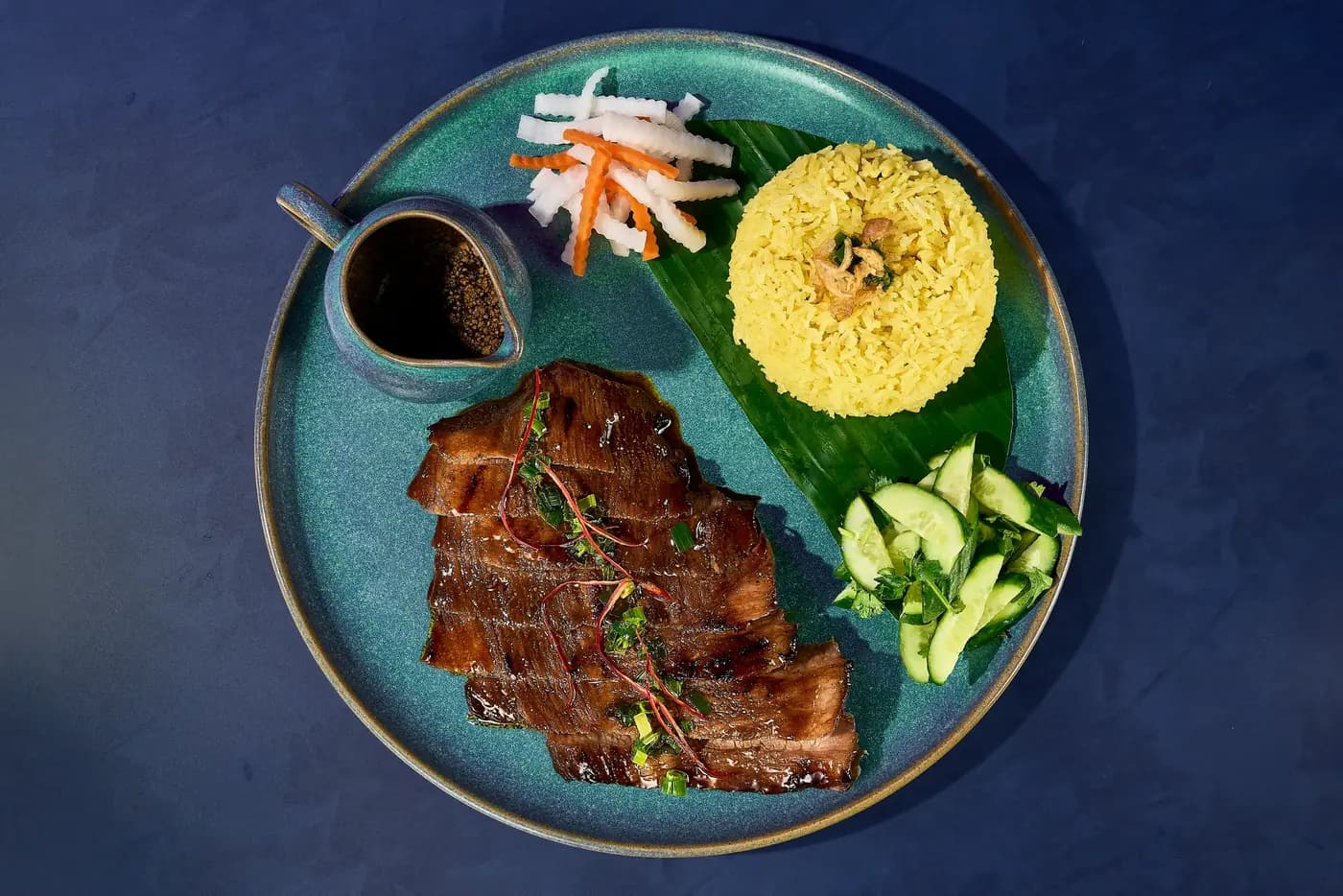 Grilled ribs, turmeric rice and cucumber on a teal plate, Premiere Village