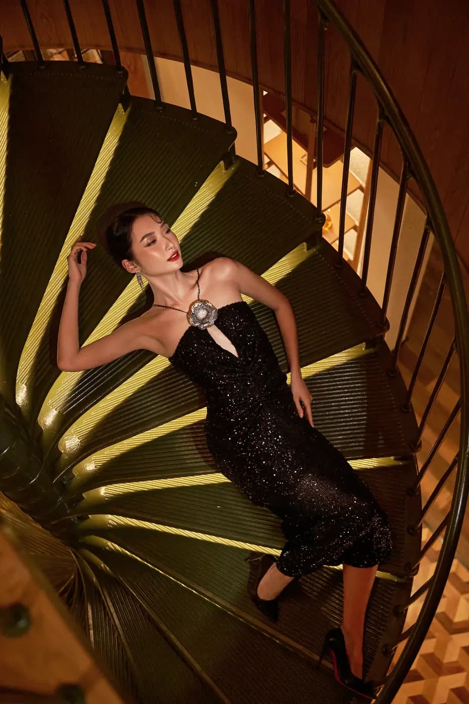 A model in a black dress on a spiral staircase, XITA x Hoiana
