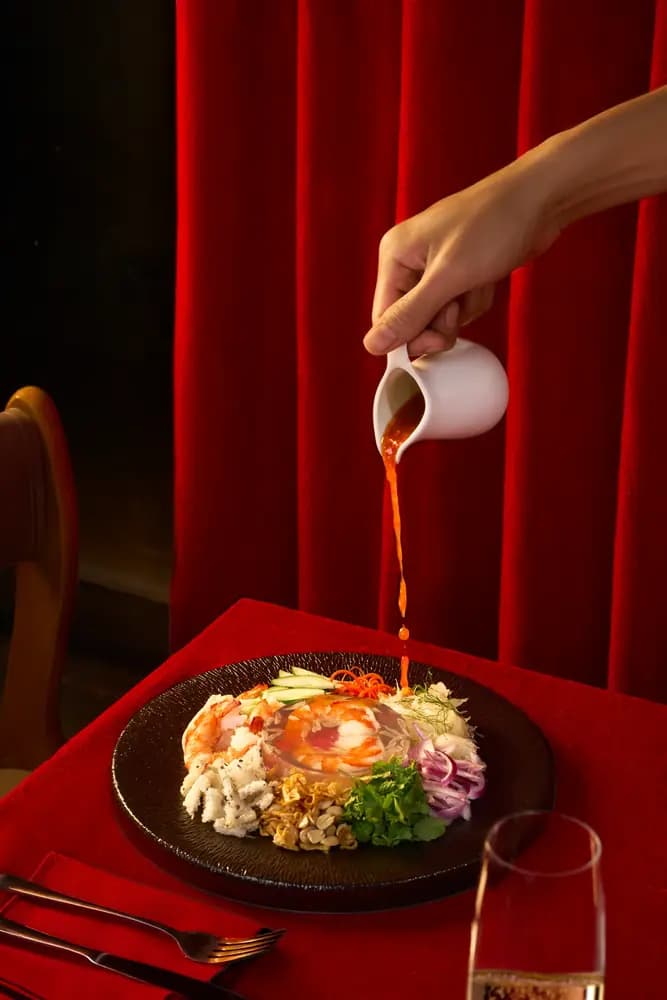 Sauce poured over a dish on a red tablecloth, Moulin de Da Nang